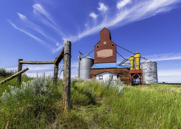 前景にフェンスの柱と草を持つサスカチュワン州 カナダの歴史的なキャデラック穀物エレベーター — ストック写真