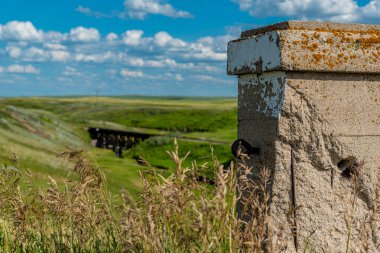Pillar from the historic concrete bridge in Scotsguard, SK with a wooden railway tressle in the background