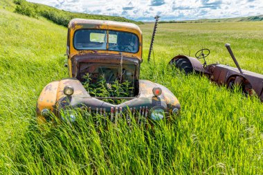 Wymark, SK / Kanada - 28 Haziran 2020 Terk edilmiş klasik sarı Ford kamyonet ve Massey Harris traktörü