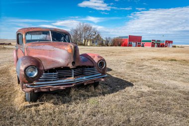 Saskatchewan 'da terk edilmiş eski bir araba ve hayalet bir kasabada binalar.