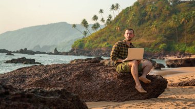 Sahilde koşan adam. Çalışma ve dinlenme. Dizüstü bilgisayar ile serbest meslek