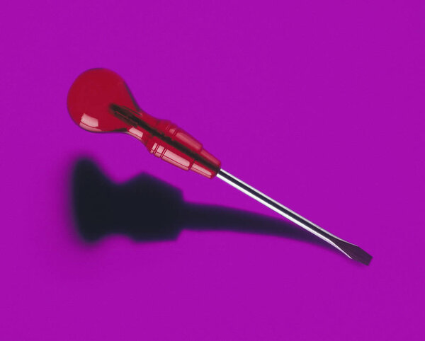 SCREWDRIVER CASTING SHADOW ON PURPLE BACKGROUND