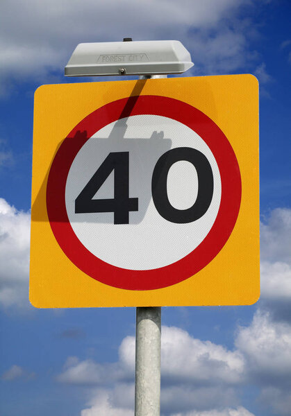 ROAD TRAFFIC SPEED LIMIT SIGN 40 MPH ISOLATED ON BLUE SKY AND CLOUDS BACKGROUND