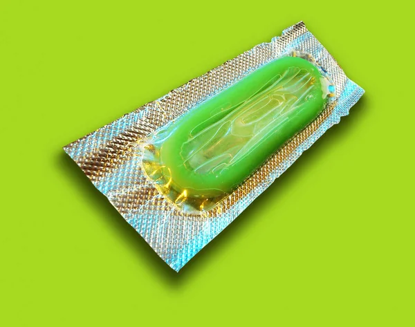 绿色背景下的铝箔包装单绿色避孕套 — 图库照片