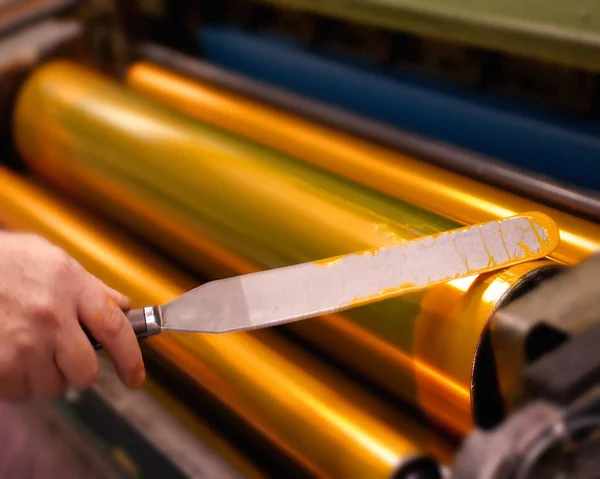 PRINTER APPLYING INK TO ROLLERS OF PRINTING PRESS