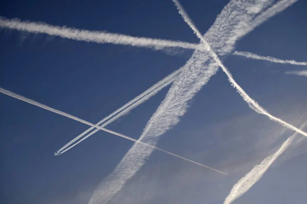 Flugzeugdampfspuren gegen strahlend blauen Himmel lizenzfreie Stockbilder