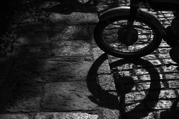 Detail of the wheel of a motorbike and his shadow. Black and white photography