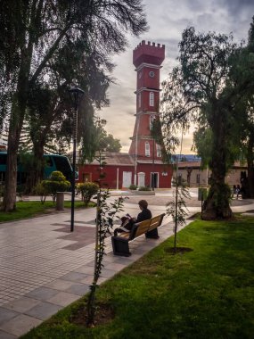 Main square of Vicuna, with the tower of the town hall. Elqui valley in Chile, a woman reading in a brench clipart