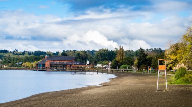 Beach at Frutillar village in Chile. Lake llanquihue with the Lake theatre in the back clipart