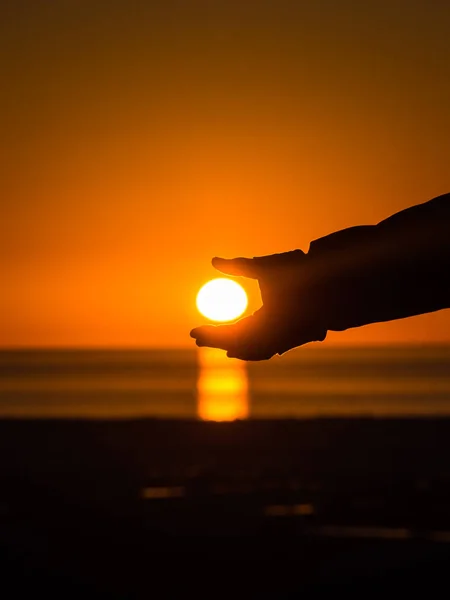 Mão pegando o sol durante o pôr do sol . — Fotografia de Stock