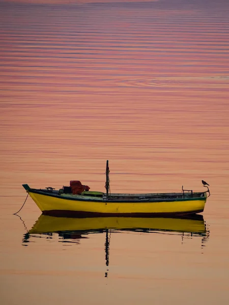 Little boat floating on the calm water under amazing sunset in Q