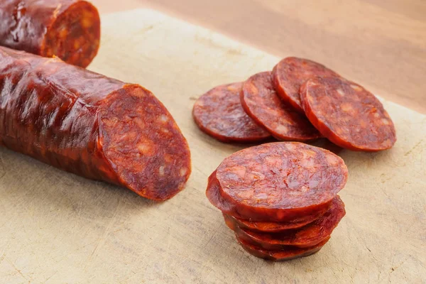 Chorizo ibérico, chorizo español o salchicha española cortada en rodajas sobre una tabla de madera. Plato típico español — Foto de Stock