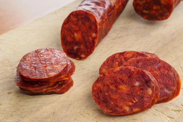 Chouriço ibérico, chouriço espanhol ou linguiça espanhola cortada em fatias em uma tábua de madeira. Prato típico espanhol — Fotografia de Stock