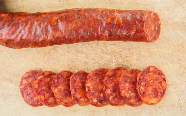 Chorizo ibérico, chorizo español o salchicha española cortada en rodajas sobre una tabla de madera. Plato típico español — Foto de Stock