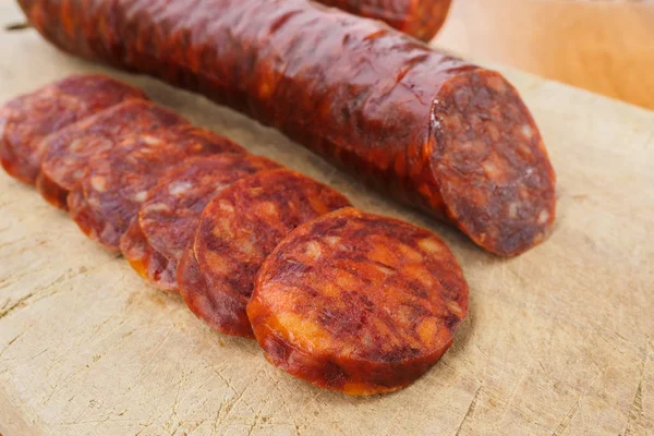 Chouriço ibérico, chouriço espanhol ou linguiça espanhola cortada em fatias em uma tábua de madeira. Prato típico espanhol — Fotografia de Stock