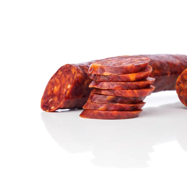 Iberische Chorizo, spanische Chorizo oder spanische Wurst mit Scheiben übereinander auf weißem Hintergrund mit seinem Spiegelbild, typische Tapa — Stockfoto