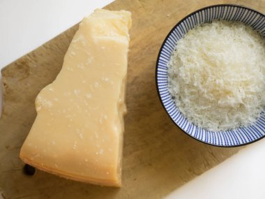 Beyaz arka plan üzerinde bir kapta rendelenmiş parmesan peyniri