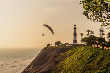 Gün batımında Lima şehrinin kayalıklarında yamaç paraşütü