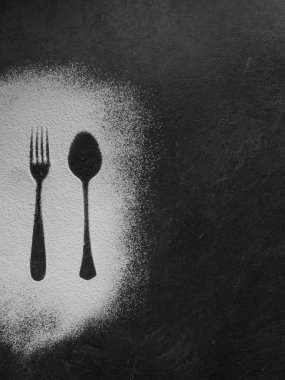 Koyu doku arka planda un ile yapılan kaşık ve çatal siluet