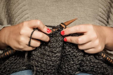 Kırmızı tırnaklı kız ahşap iğneler ile koyu gri yün örme