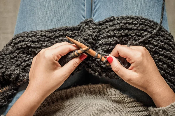 Kırmızı tırnaklı kız ahşap iğneler ile koyu gri yün örme