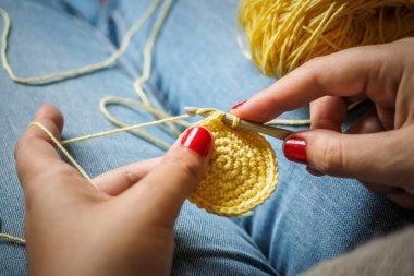 Sarı iplik ve çivi kırmızı boyalı tığ işi yapan kız