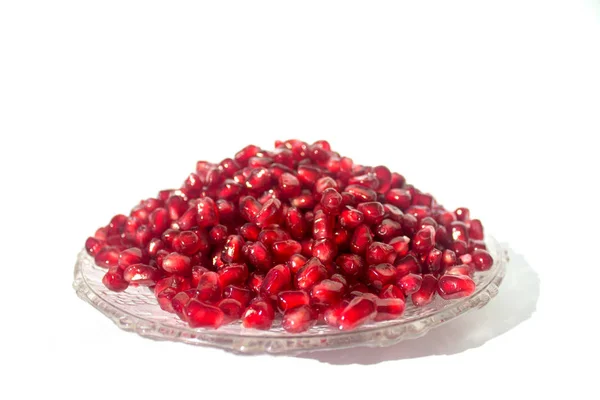 Pomegranate grains on a plate.  Isolated on white. — Stock Photo, Image