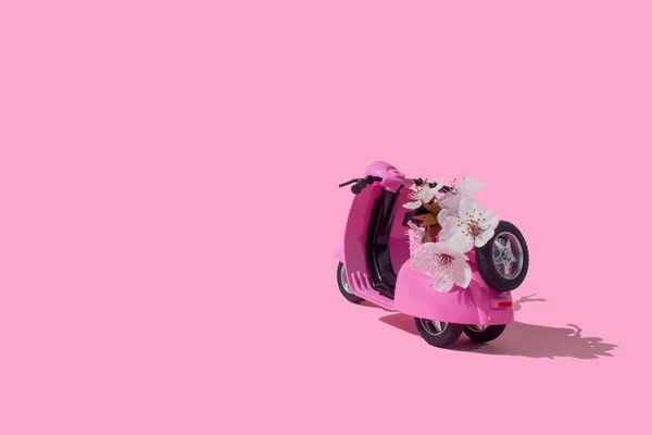Pink retro toy bike delivering bouquet of flowers box on pink background. February 14 card, Valentine's day. Flower delivery. 8 March, International Happy Women's Day. Mother's day.