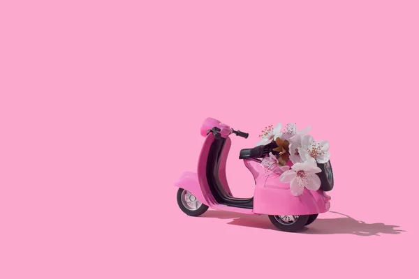 Pink retro toy bike delivering bouquet of flowers on pink background. February 14 card, Valentine\'s day. Flower delivery. 8 March, International Happy Women\'s Day. Mother\'s day