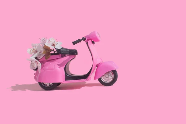 Pink retro toy bike delivering bouquet of flowers box on pink background. February 14 card, Valentine\'s day. Flower delivery. 8 March, International Happy Women\'s Day. Mother\'s day