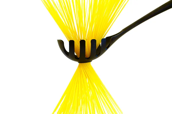 Сырые длинные желтые спагетти в черной ложке изолированы на белом — стоковое фото