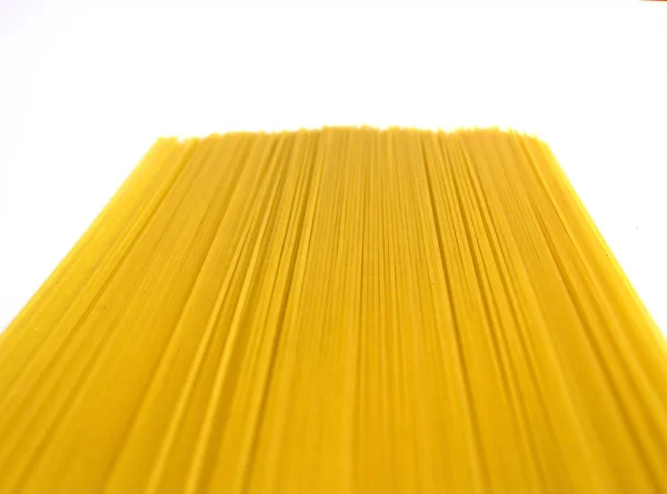 Сырые длинные желтые спагетти с перспективой, изолированные на белом — стоковое фото
