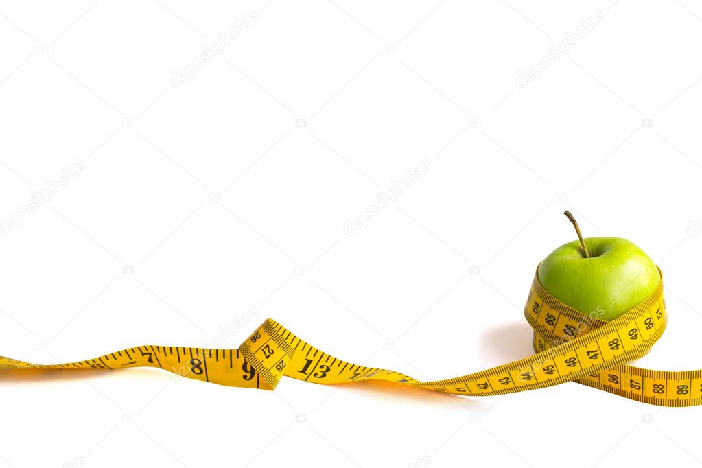 Green apple and measuring tape  with centimeters and inches isolated on white background.