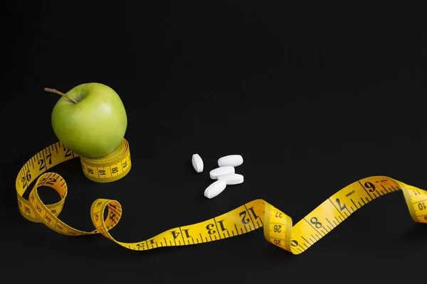 Pomme verte, pelures blanches et ruban à mesurer avec centimètres et pouces isolés sur fond noir — Photo