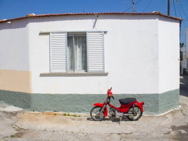 Yunanistan, Rodos, Nisan 2019. Geleneksel beyaz köy evinin yanında kırmızı motosiklet