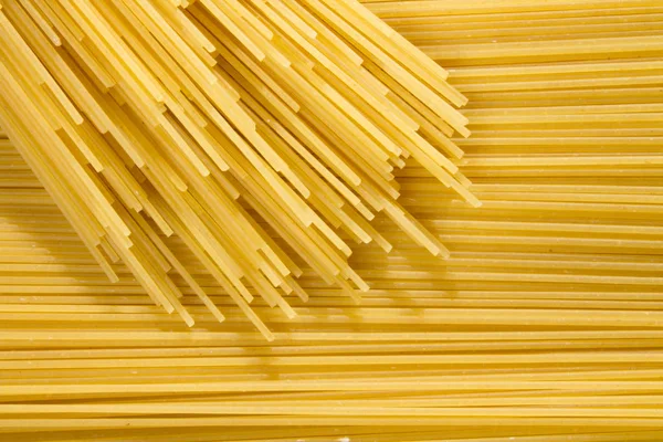 Фон длинной сырой желтой спагетти-пасты в хонтальном плане, а сверху много макарон . — стоковое фото