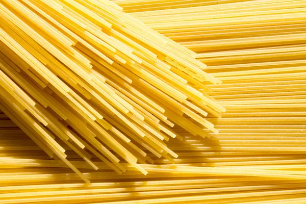 Фон длинного сырого желтого спагетти-пасты в хонтальном плане и повязка макарон сверху . — стоковое фото
