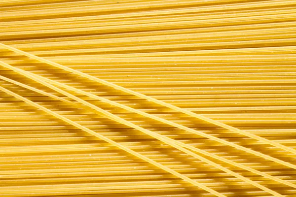 Фон длинной сырой желтой спагетти-пасты в хонтальном плане и немного макарон сверху . — стоковое фото
