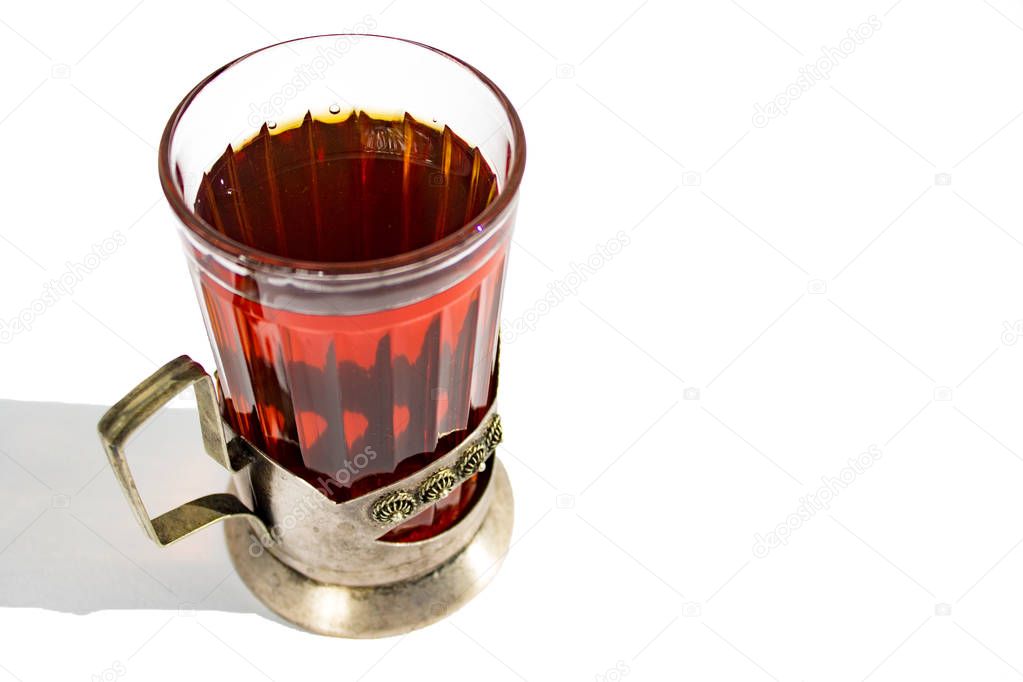 strong hot black tea in a glass Cup in a metal Cup holder on a white background with a shadow.