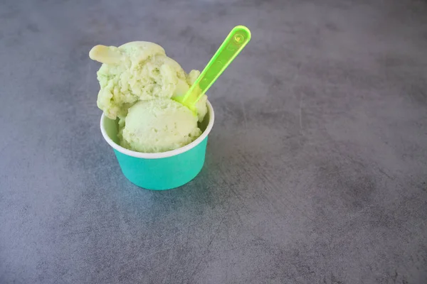 Зеленое яблоко мороженое сорбет в бирюзовой бумаге Чашка на сером каменном столе Стоковое Изображение