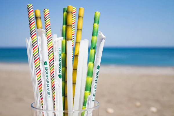 Plusieurs remplacements de tubes à cocktail en plastique, bioplastiques et bambou dans le verre en fond bleu avec plage . Photos De Stock Libres De Droits