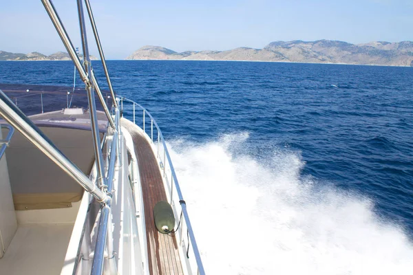 side front of the motor yacht going in the sea towards the mountains