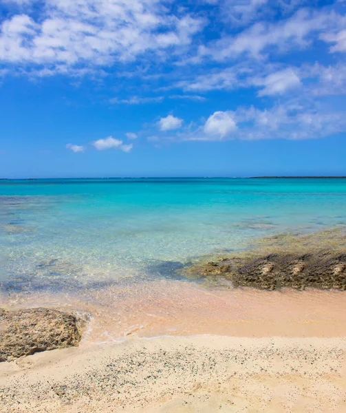 푸른 하늘에 핑크 색 모래, 돌, 청록색 물과 구름이 있는 해변. — 스톡 사진