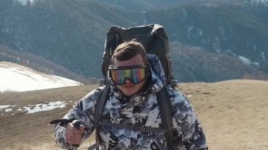 Bir turist trekking Polonyalılar ile ve bir arka plan bahar karla kaplı dağların büyük bir sırt çantası tırmanıyor bir üst ve bir termos çay içmeye bir durdurmak için durur. 4 k slowmotion.