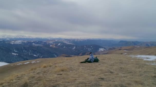 トレッキング ポールが観光と春の雪をかぶった山々 を背景に巨大なバックパック トップとポットからお茶を飲むを停止の位置に上昇します のスローモーション — ストック動画
