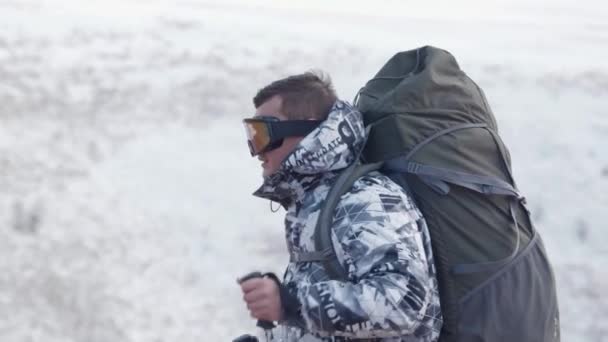 トレッキング ポールが観光と春の雪をかぶった山々 を背景に巨大なバックパック トップとポットからお茶を飲むを停止の位置に上昇します スローモーション — ストック動画