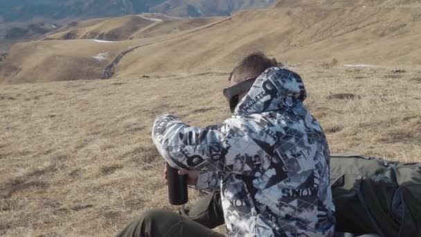 在春天 一位带着徒步杆和一个巨大背包的游客爬上山顶 停下来喝热水瓶的茶 慢动作 — 图库视频影像