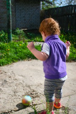 Küçük kızıl saçlı kız, bir yaşında, yaşını çalışır yard bir sıcak yaz gününde birçok dandelions ve yeşil çim onun etrafında büyümek.