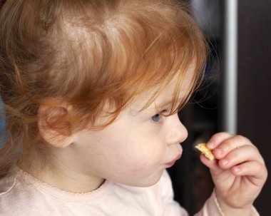 Kızıl saçlı küçük kız kurabiye yiyor