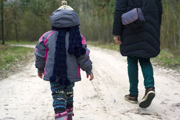 Mãe e filha estão andando na floresta de primavera. bebê e mãe caminham ao longo da estrada da floresta pela mão — Fotografia de Stock